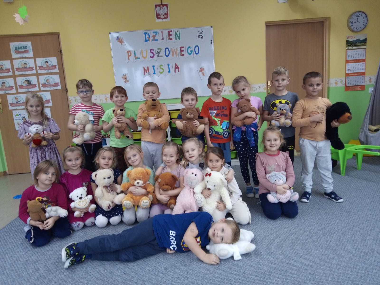 Grupa starszaków trzymających misie na tle napisu Dzień Pluszowego Misia