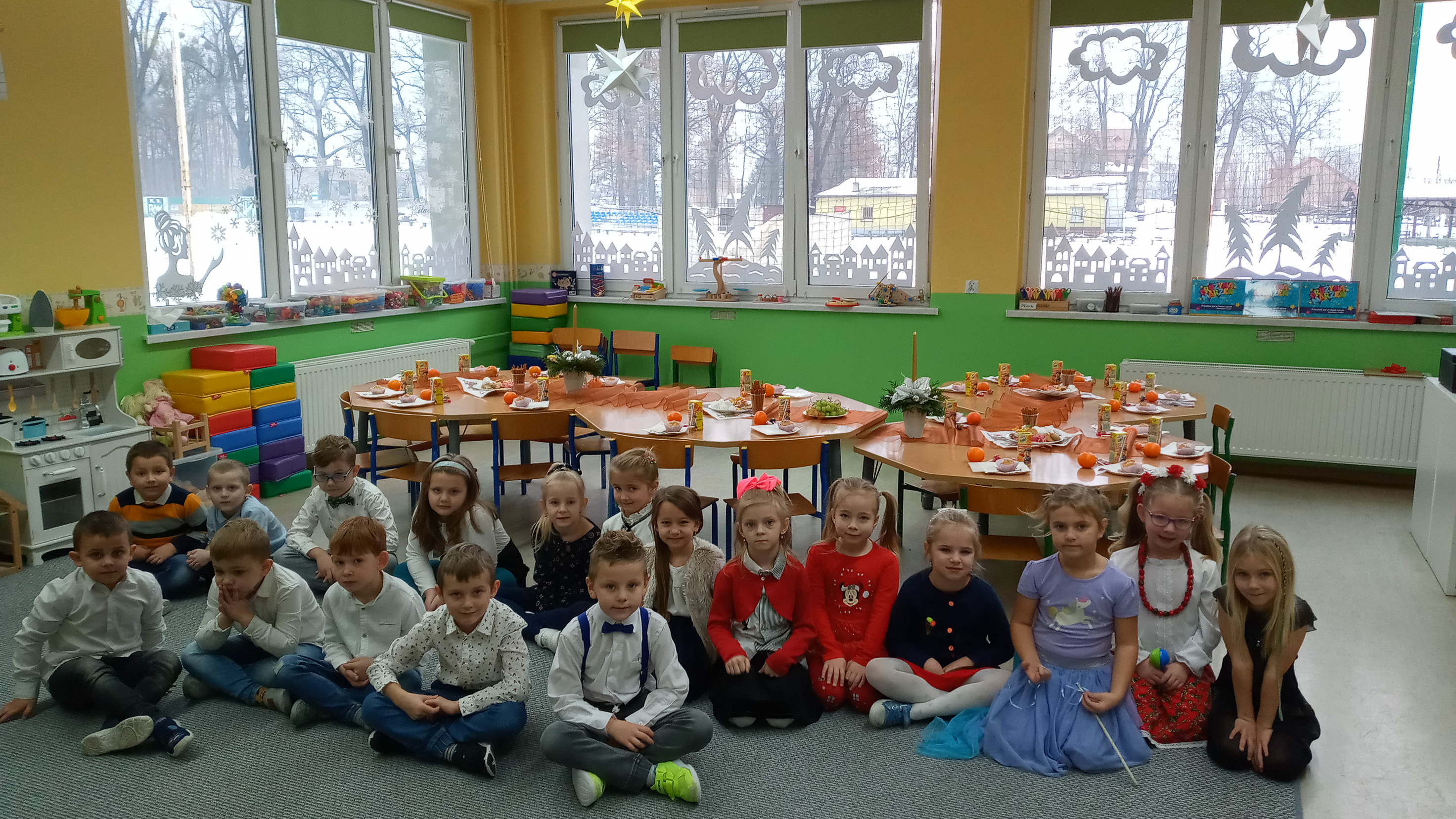 Grupa maluchów na tle świątecznego wystroju trzyma w ręce prezenty