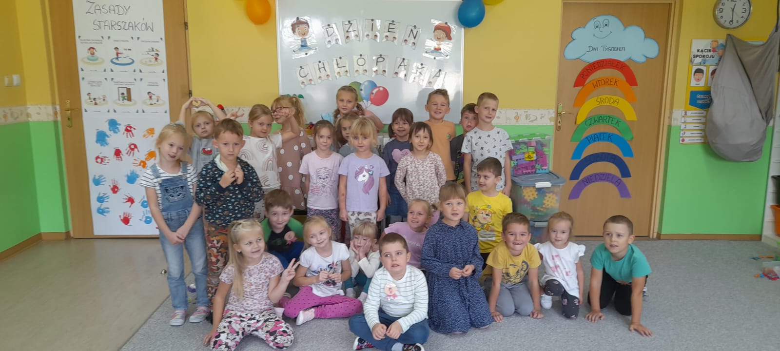 Grupa starszaków pozuje na tle napisu dzień chłopaka