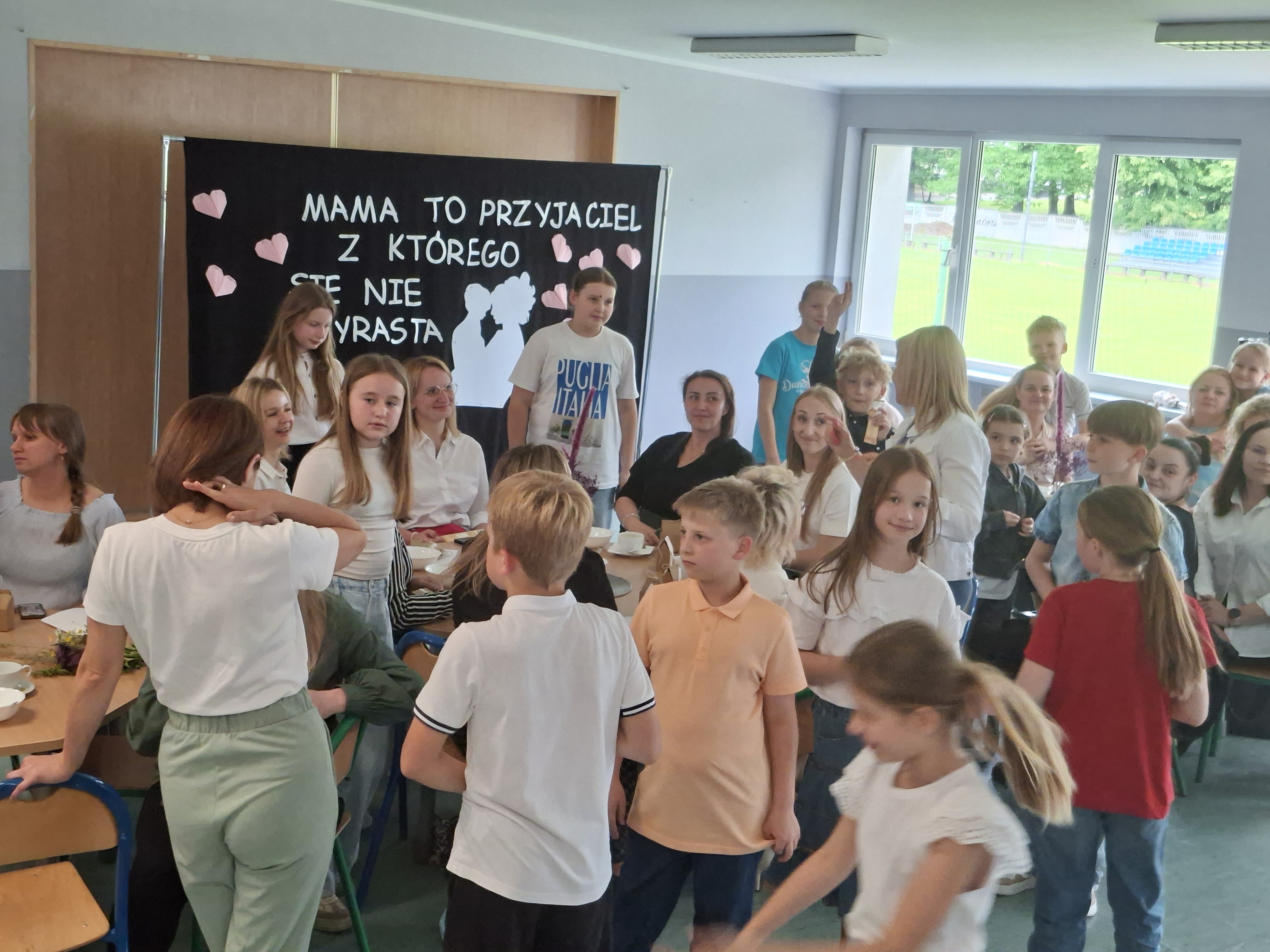 Uczniowie klasy czwartej wraz z mamami w trakcie uroczystości klasowej.