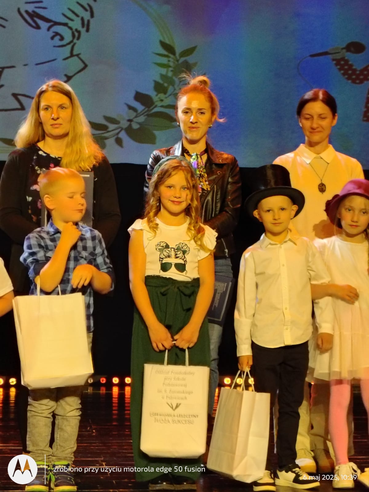 Trójka dzieci wraz ze swoimi opiekunami pozuje z nagrodami.